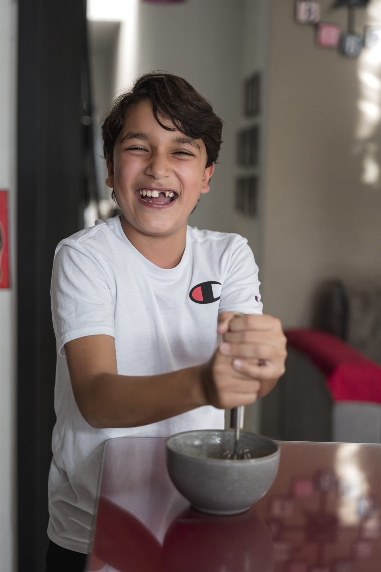 Niño riendo mientras bate una preparación en un tazón