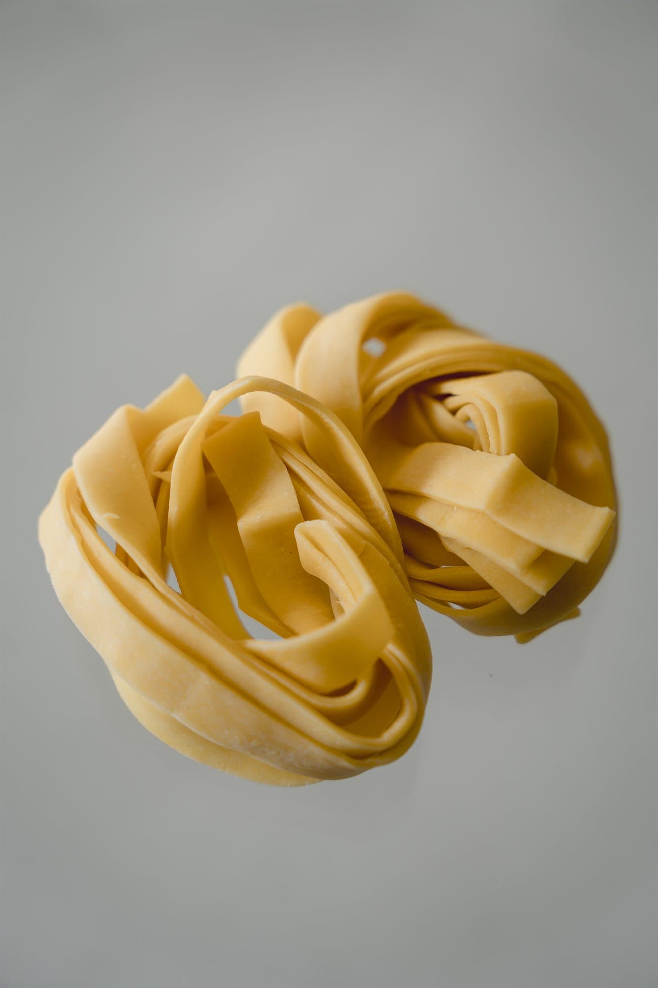 Nido de tagliatelle fresco sobre fondo claro