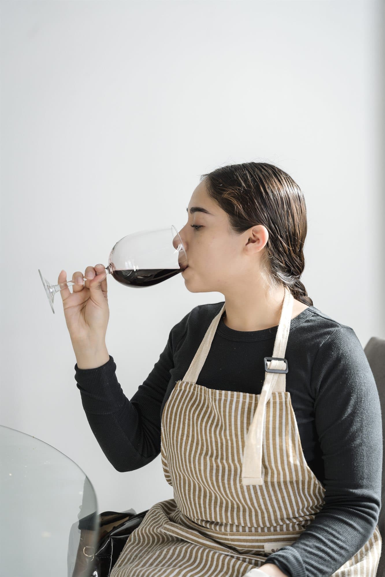 Mujer catando una copa de vino tinto sobre fondo neutro